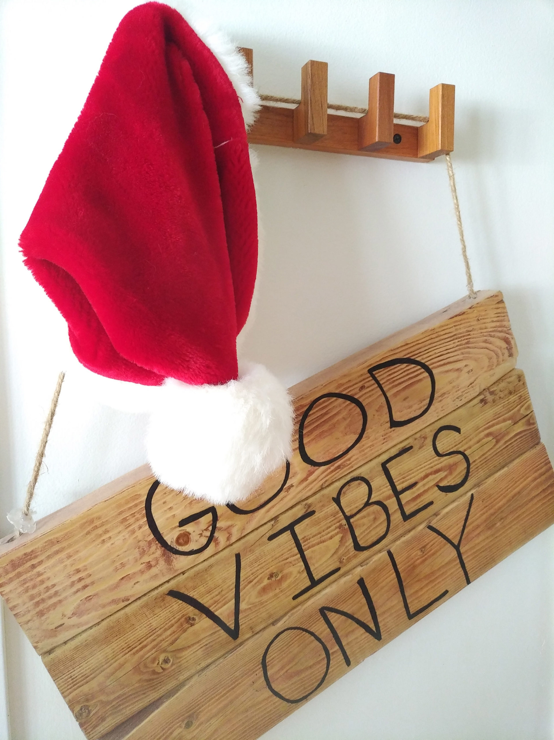Santa hat on wooden rack with a wooden sign that says "GOOD VIBES ONLY"